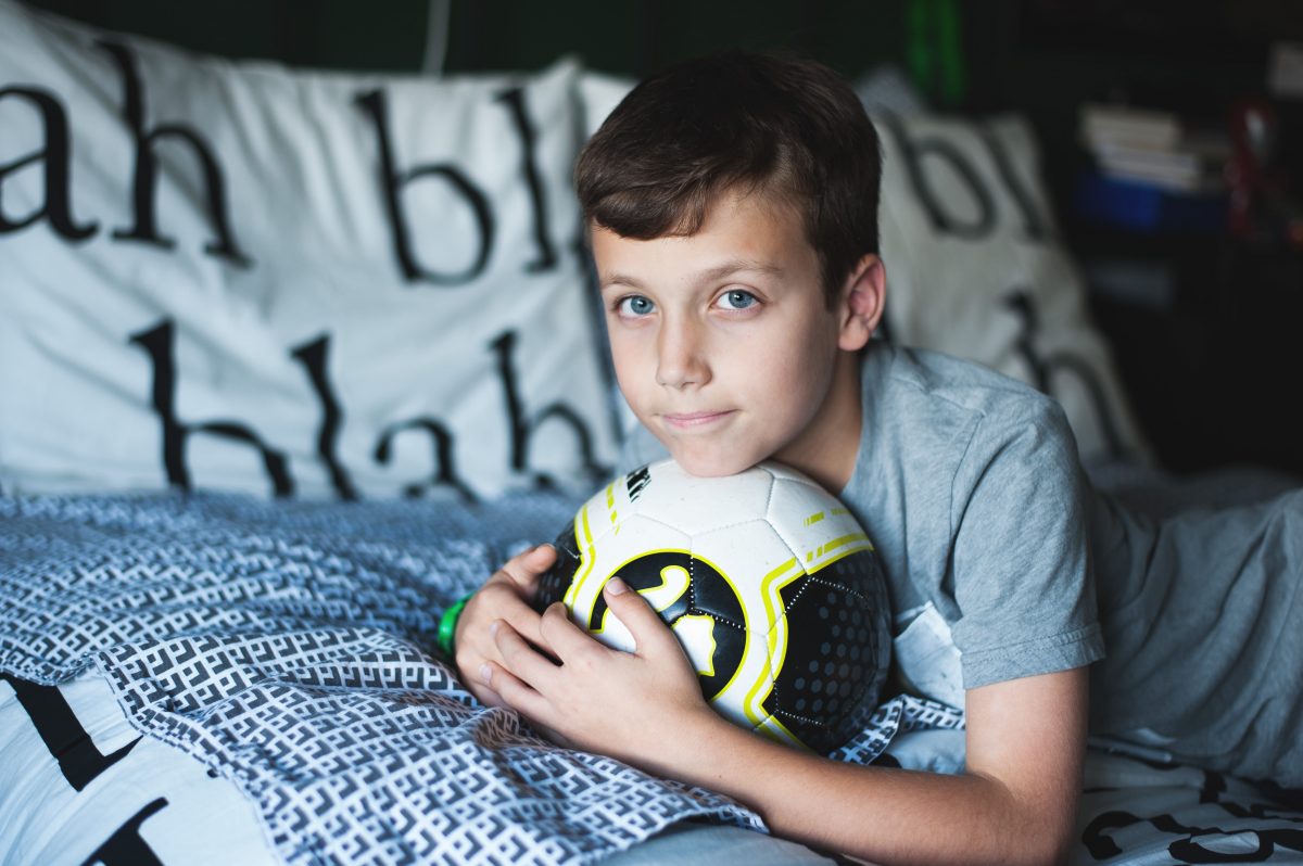Photographers in Greensboro NC with tween boy on bed with soccer ball