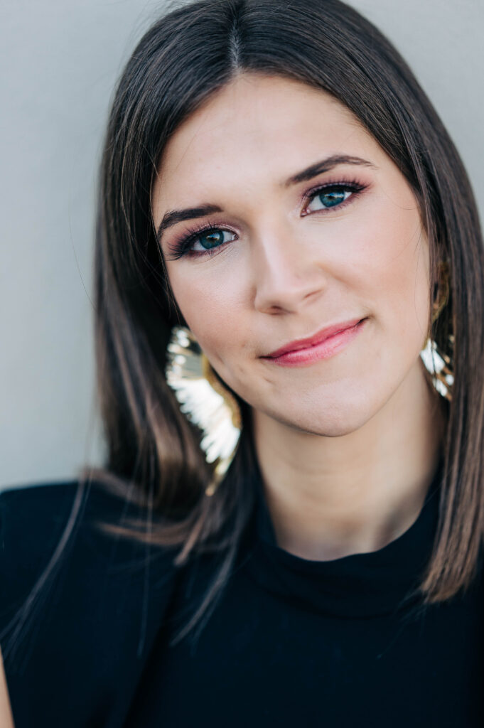 Close up of senior girl wearing gold feather earrings and a black top