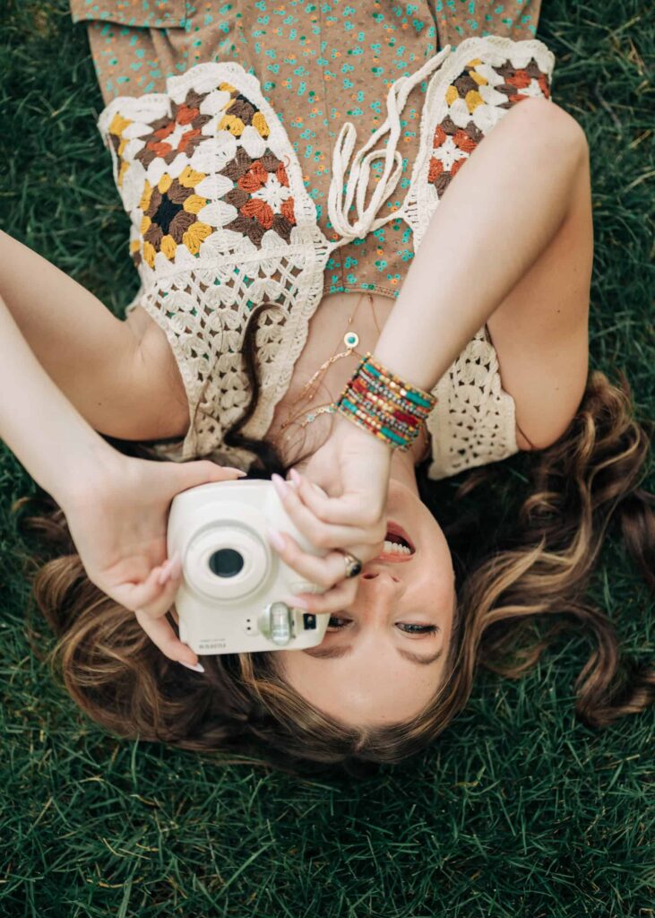 Senior girl laying down with an instamax camera