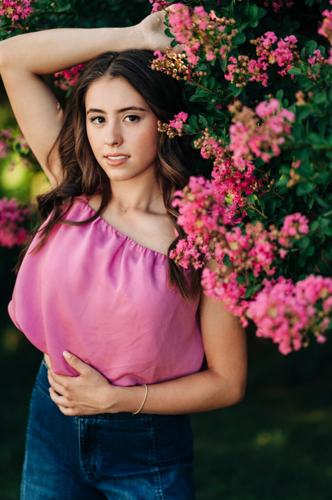 Senior girl in pink top standing among a blooming pink tree in Greensboro NC